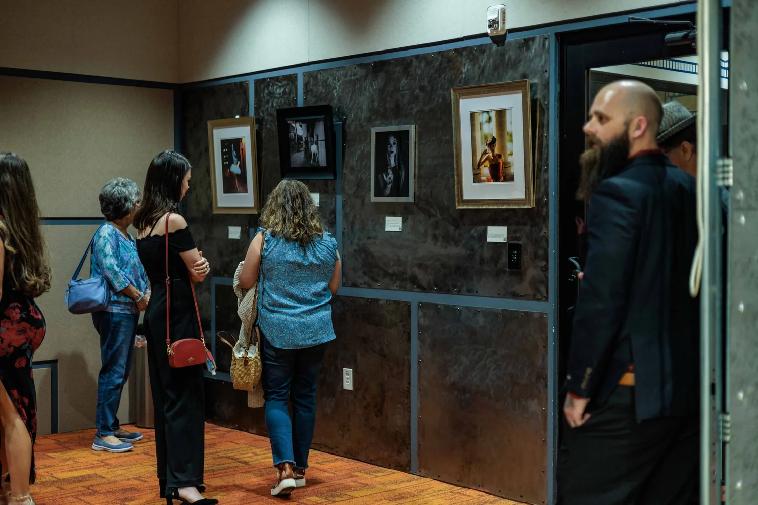 People viewing artwork at a gallery exhibition.